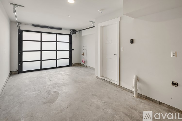 A spacious room with a white door and a garage door opener.