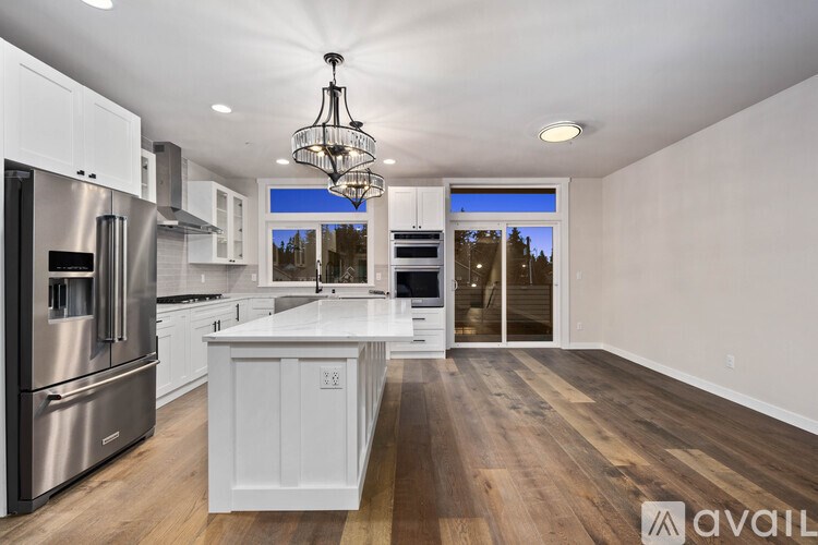 A modern kitchen with wooden floors and stainless steel appliances.