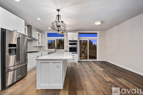 A modern kitchen with wooden floors and stainless steel appliances.