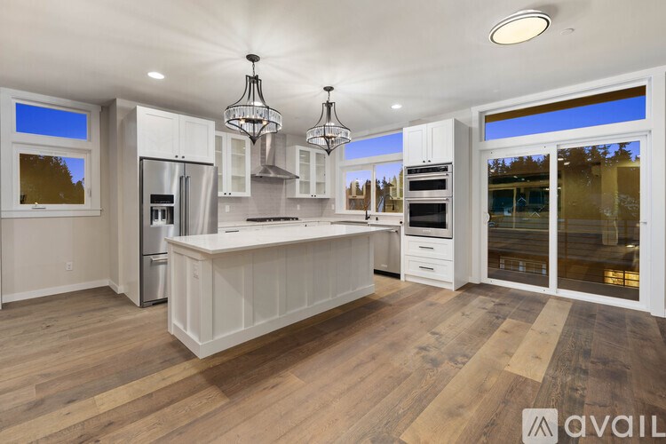 A modern kitchen with wooden floors and white cabinetry.