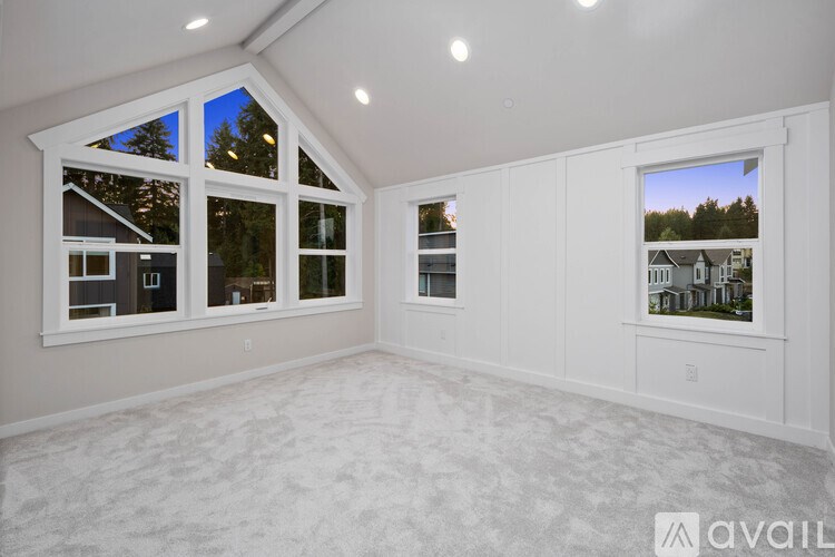 A spacious room with large windows and a carpeted floor.