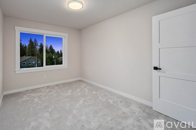 A room with a window showing a house and trees outside.