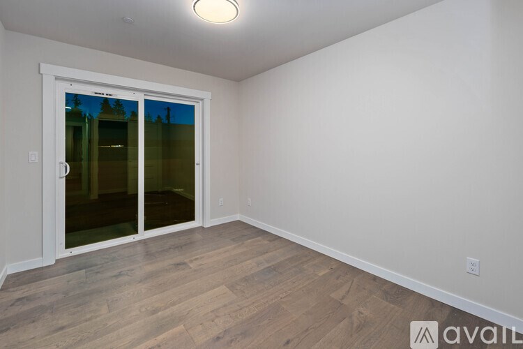 A room with a sliding glass door and wooden flooring.