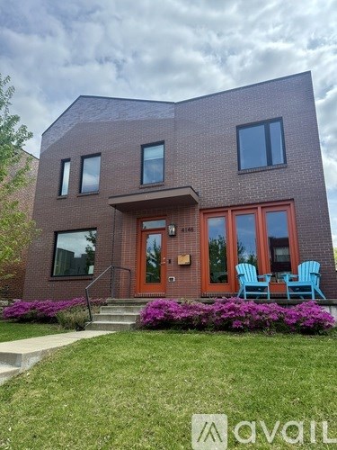 A house with a red door and windows is surrounded by greenery.