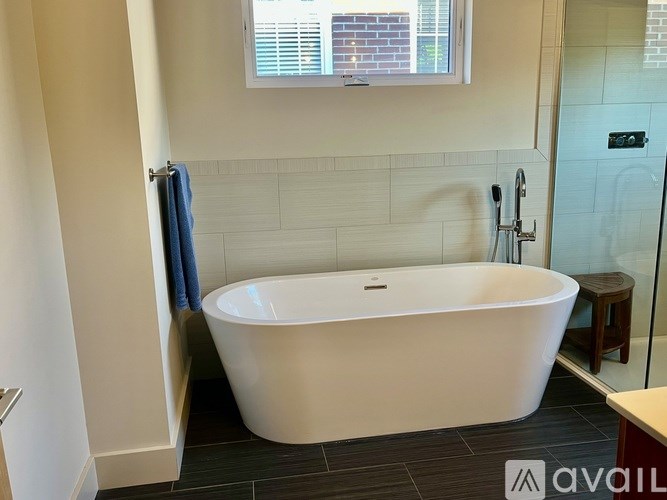 A white bathtub is in a bathroom with a blue towel hanging on the side.