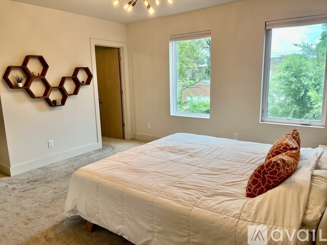 A bedroom with a bed, a window, and a wall decoration.