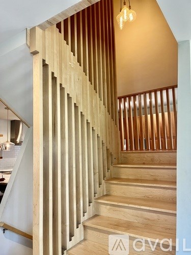 A wooden staircase with a light brown hue and a white wall.