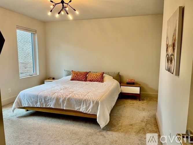 A bedroom with a bed, nightstand, and a painting on the wall.