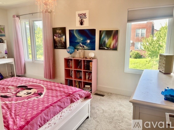 A bedroom with a pink bedspread and a Mickey Mouse design.