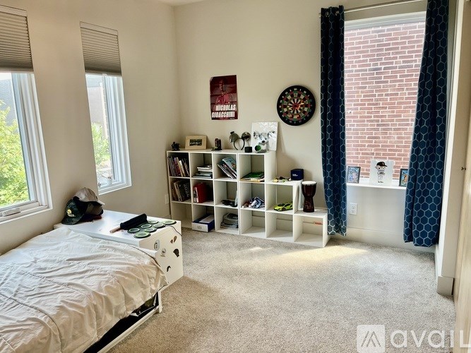 A bedroom with a bed, bookshelf, and window.