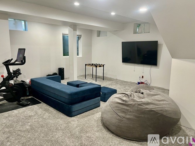 A room with a bean bag chair, a sofa, and a television.