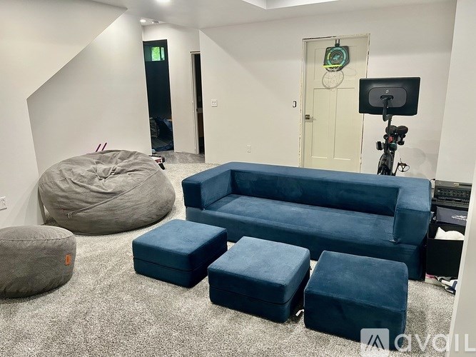 A room with a grey bean bag chair, a blue sofa, and a camera on a tripod.