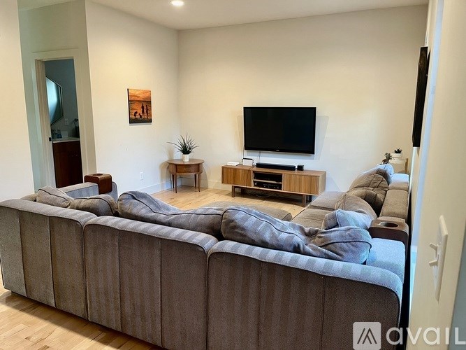 A living room with a large couch and a television on a wooden stand.