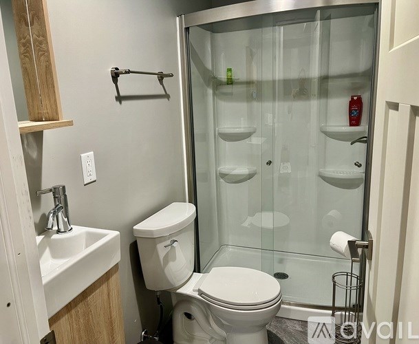 A white toilet is in a bathroom with a walk-in shower.