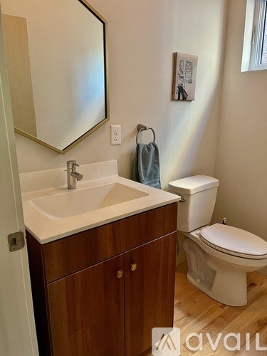 A bathroom with a toilet, sink, and mirror.