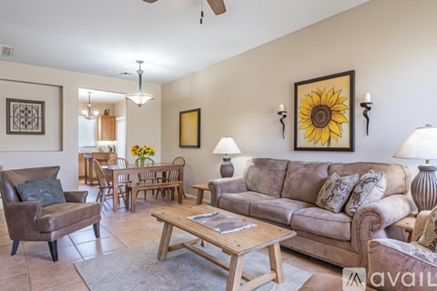 A living room with a brown couch, a wooden coffee table, and a sunflower painting on the wall.