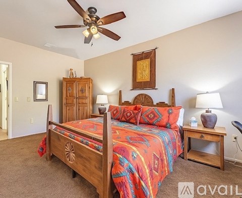 A bedroom with a bed, a ceiling fan, and a wooden cabinet.