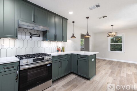 A kitchen with dark green cabinets and a stove top oven.