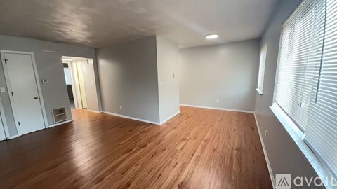 A room with wooden flooring and white walls is available for rent.