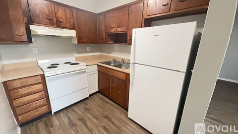 A kitchen with a white refrigerator, white stove, and wooden cabinets.