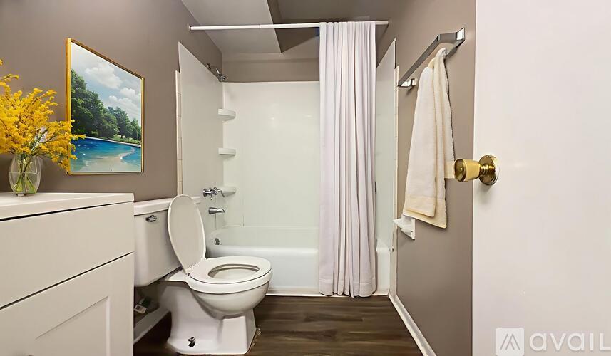 A white toilet is in a small bathroom with a white bathtub.