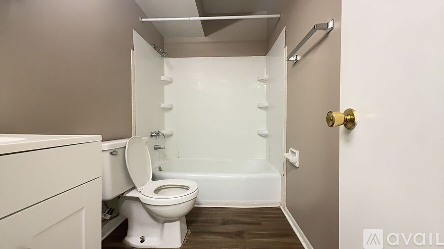 A white toilet is in a small bathroom with a white bathtub.