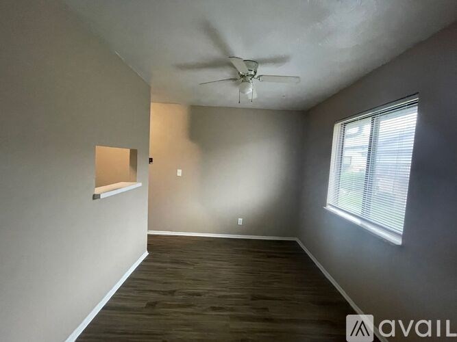 A room with a ceiling fan and a window with blinds.