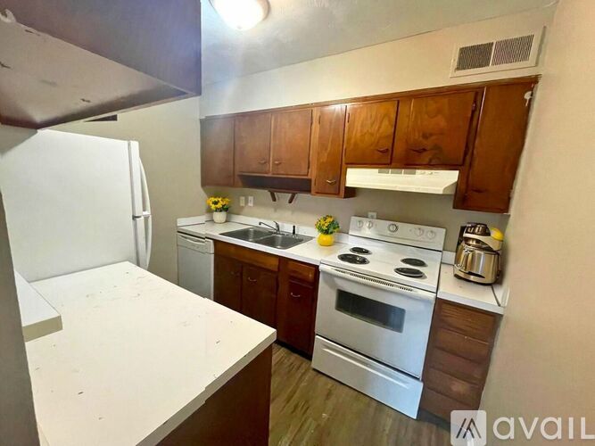 A kitchen with white appliances and wooden cabinets.