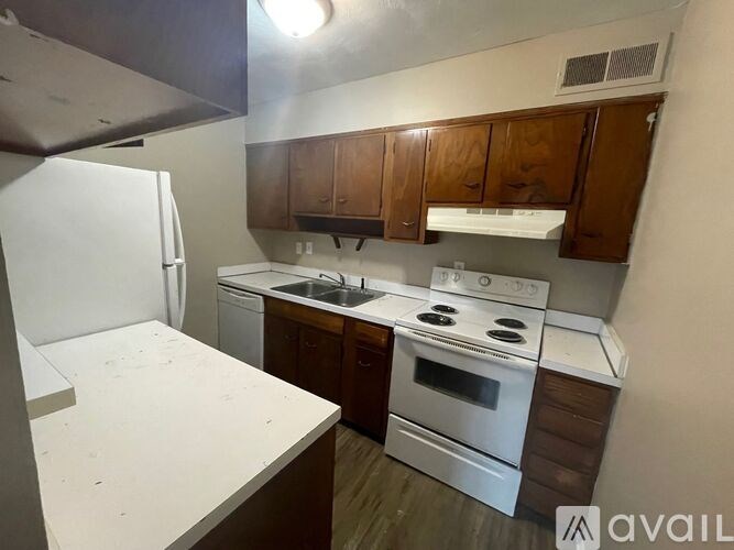 A kitchen with white appliances and wooden cabinets.