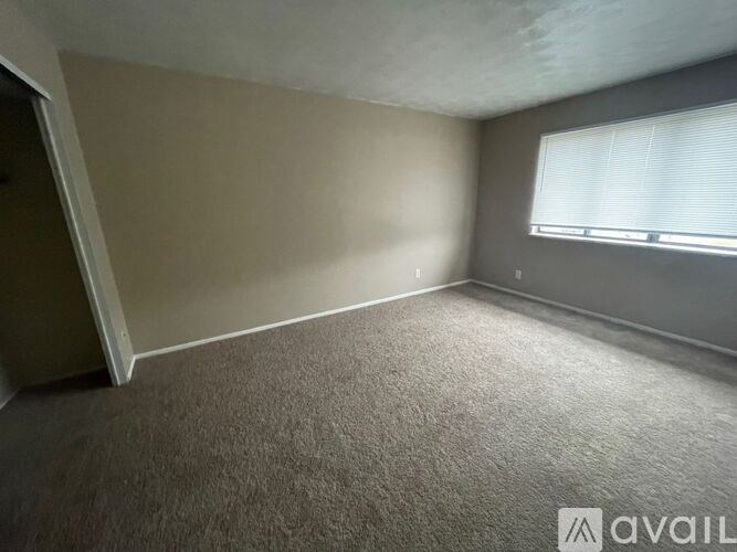 A room with a carpeted floor and a window with blinds.