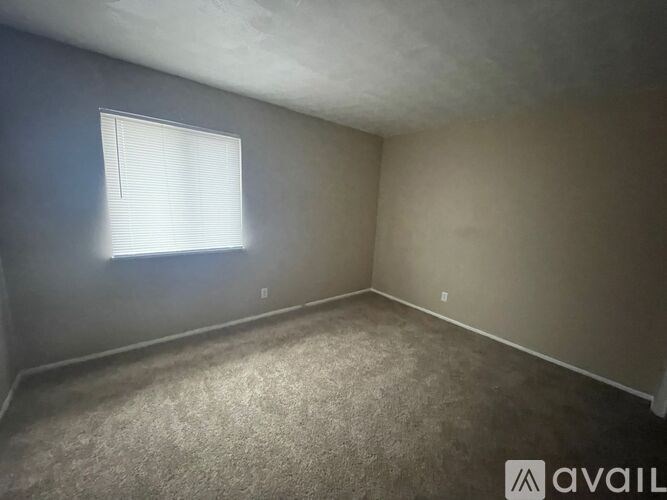A room with a carpeted floor and a window with blinds.