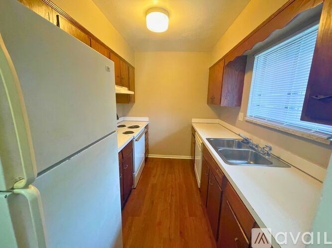A kitchen with a white refrigerator, wooden cabinets, and a sink.