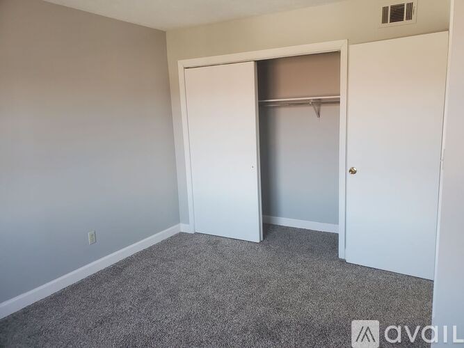 A room with a white door and a grey carpet.