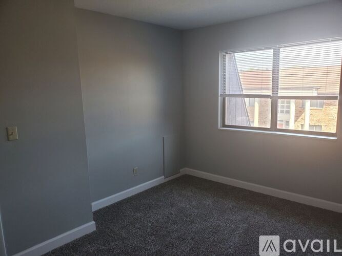 A room with a carpeted floor and a window with blinds.