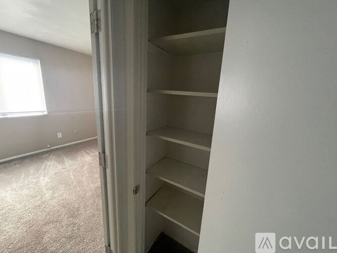 A room with a carpeted floor and a window with blinds.