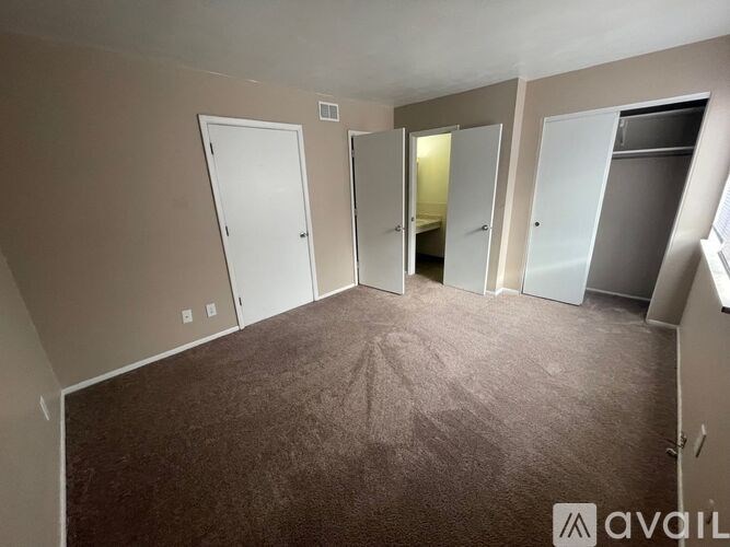 A room with carpeted floor and four doors.