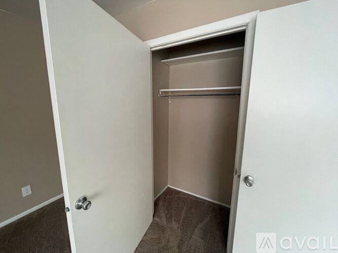 A white door with a silver handle is open to a small, carpeted room.