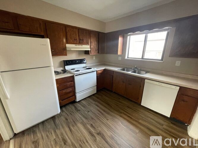 A kitchen with white appliances and wooden cabinets.