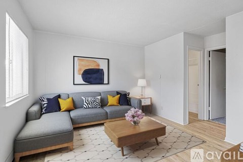 A living room with a grey couch, a wooden coffee table, and a painting on the wall.