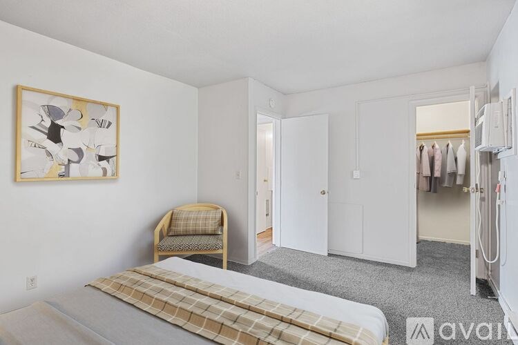 A bedroom with a bed, chair, and artwork on the wall.