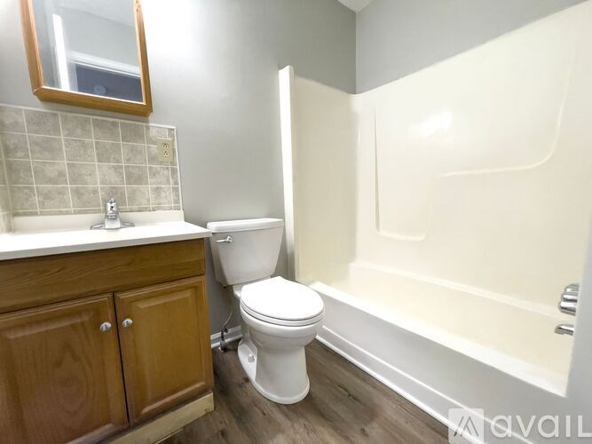 A white toilet sits next to a white bathtub in a bathroom.