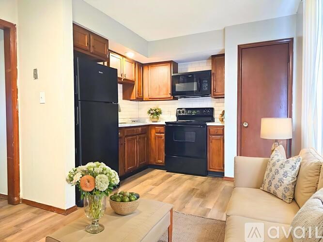 A kitchen with a black fridge, black oven, and wooden cabinets.