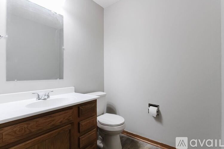 A bathroom with a toilet, sink, and mirror.
