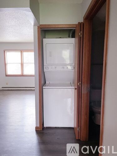A white dishwasher is in a kitchen with a wooden door.