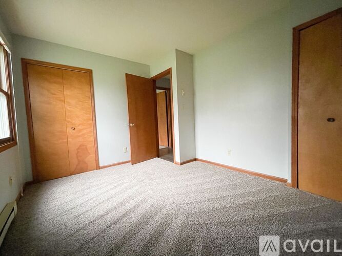 A room with a carpeted floor and three doors.