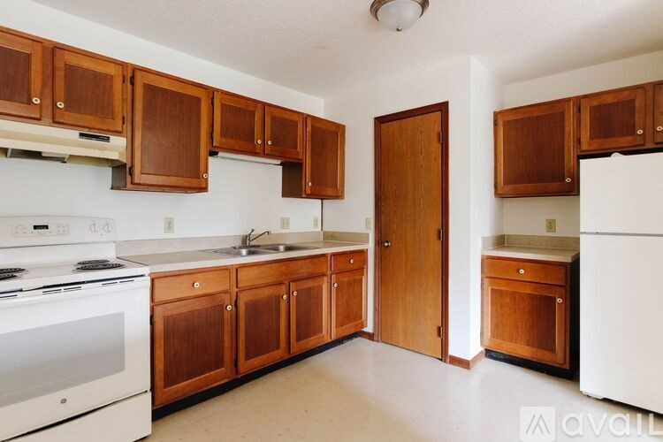 A kitchen with wooden cabinets and a white stove.