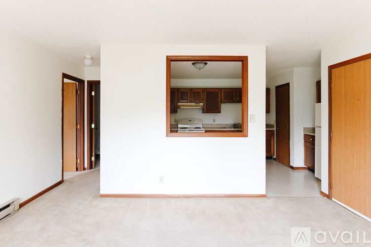 A kitchen area is visible through a window in a white room.