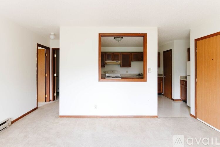 A kitchen area is visible through a window in a white room.
