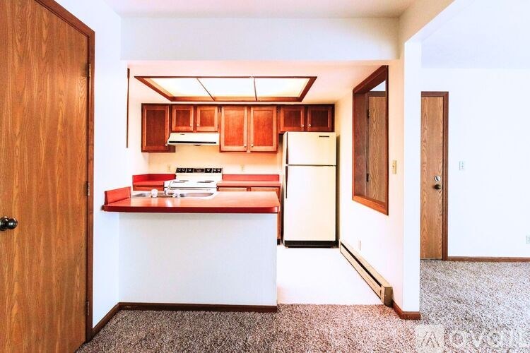 A kitchen with a white refrigerator and wooden cabinets.
