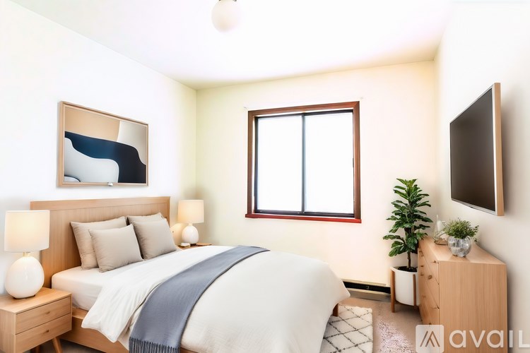 A well-lit bedroom with a bed, nightstand, and a window.
